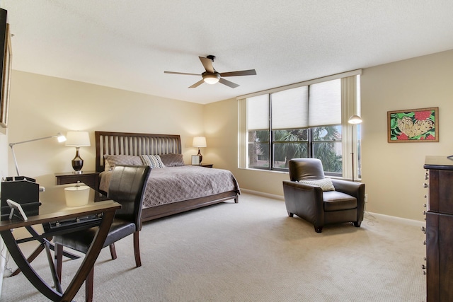 bedroom featuring light carpet, ceiling fan, baseboards, and a textured ceiling