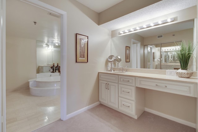 bathroom featuring visible vents, vanity, baseboards, and a bath