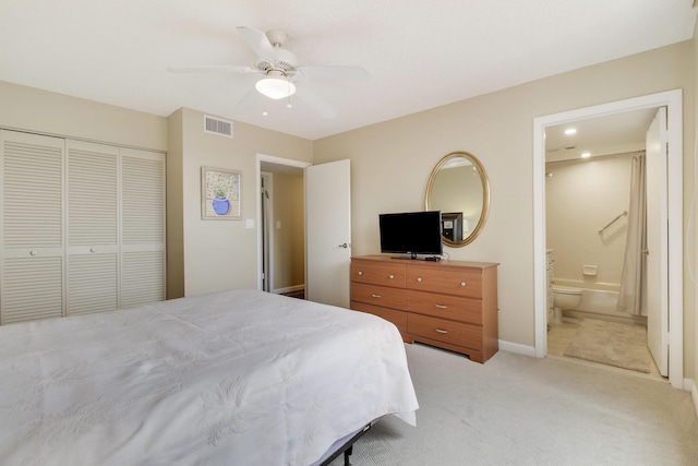 bedroom featuring a closet, light colored carpet, visible vents, a ceiling fan, and ensuite bath