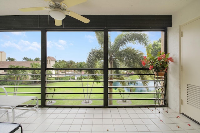 unfurnished sunroom featuring a ceiling fan, a water view, and plenty of natural light