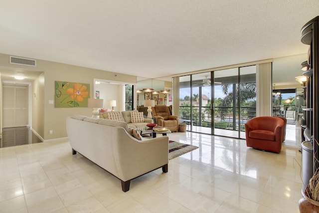 living area with light tile patterned floors, visible vents, expansive windows, a textured ceiling, and baseboards