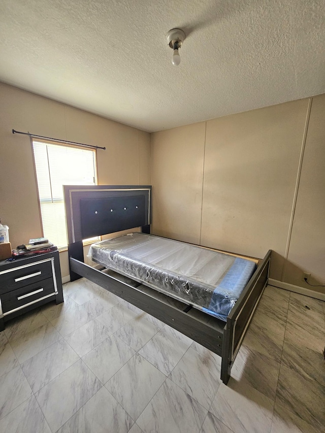 bedroom with a textured ceiling and marble finish floor