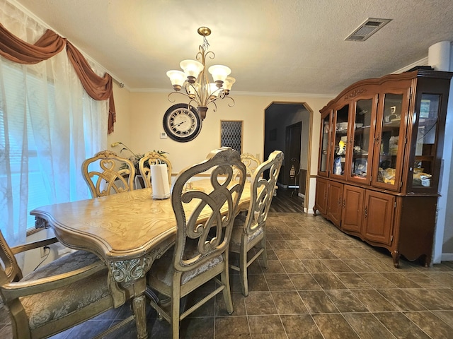 dining area with visible vents, arched walkways, ornamental molding, an inviting chandelier, and a textured ceiling