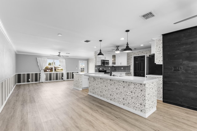 kitchen with a center island with sink, crown molding, visible vents, and stainless steel appliances