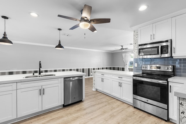 kitchen featuring white cabinets, stainless steel appliances, crown molding, and a sink