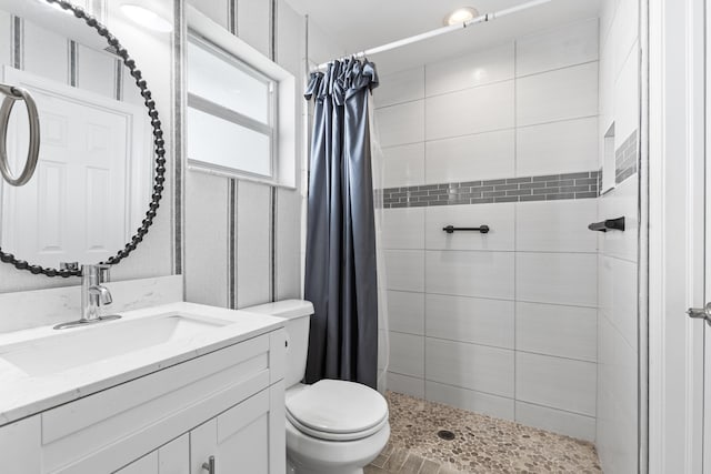 bathroom with toilet, vanity, and a tile shower