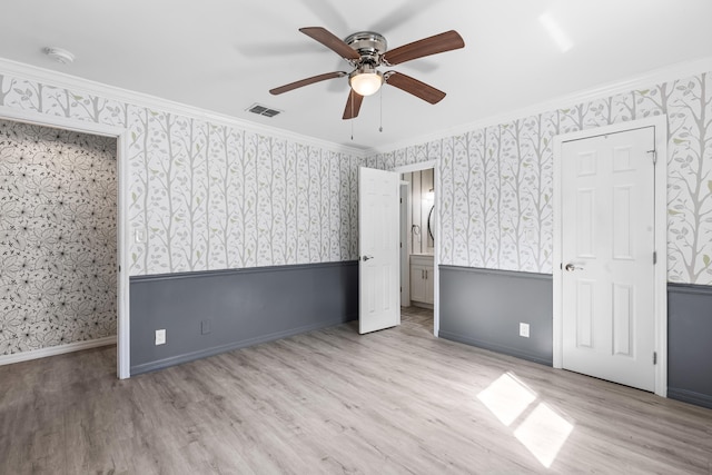 unfurnished bedroom featuring a wainscoted wall, visible vents, wood finished floors, and wallpapered walls