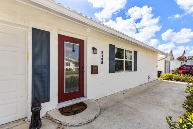 doorway to property with a garage and stucco siding