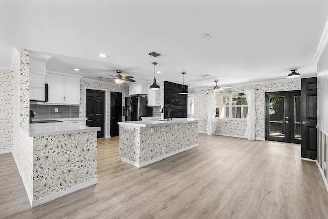 kitchen with wallpapered walls, visible vents, light countertops, and freestanding refrigerator