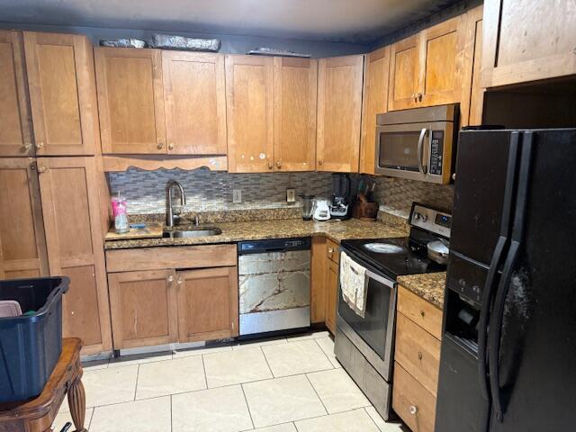 kitchen with a sink, light tile patterned flooring, tasteful backsplash, and stainless steel appliances