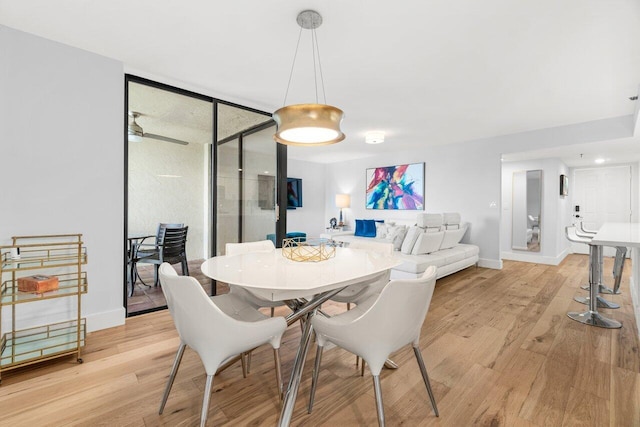 dining room featuring light wood-style flooring, floor to ceiling windows, ceiling fan, and baseboards