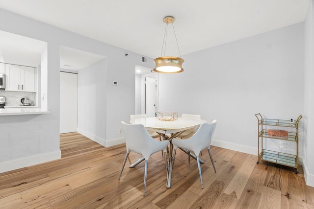 dining area featuring light wood-style floors, visible vents, and baseboards