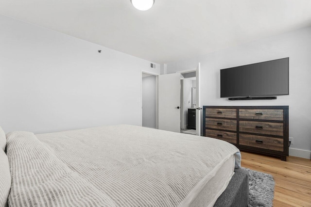 bedroom with wood finished floors, visible vents, and baseboards