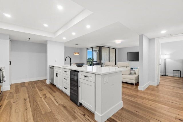 kitchen featuring beverage cooler, a sink, light wood-style flooring, and stainless steel dishwasher