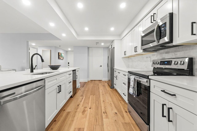 kitchen featuring light wood-style flooring, stainless steel appliances, a sink, and light countertops