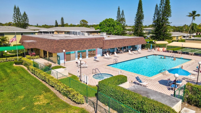 community pool with a patio, a lawn, fence, and a hot tub