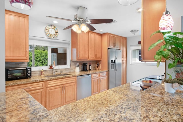 kitchen featuring a toaster, light stone counters, decorative backsplash, stainless steel appliances, and a sink