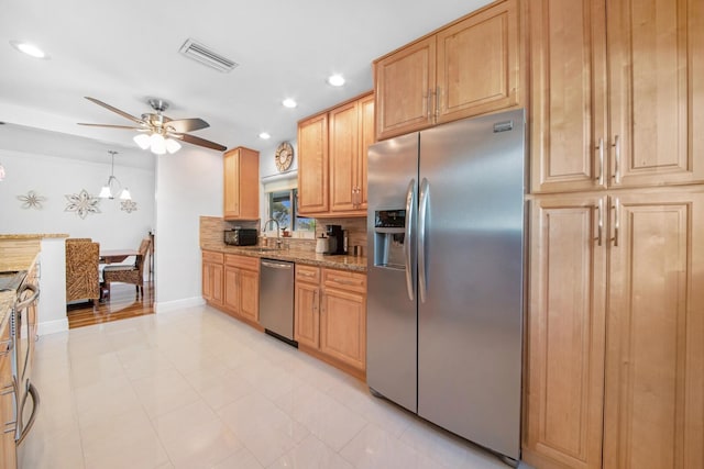 kitchen featuring visible vents, backsplash, ceiling fan, light stone countertops, and stainless steel appliances