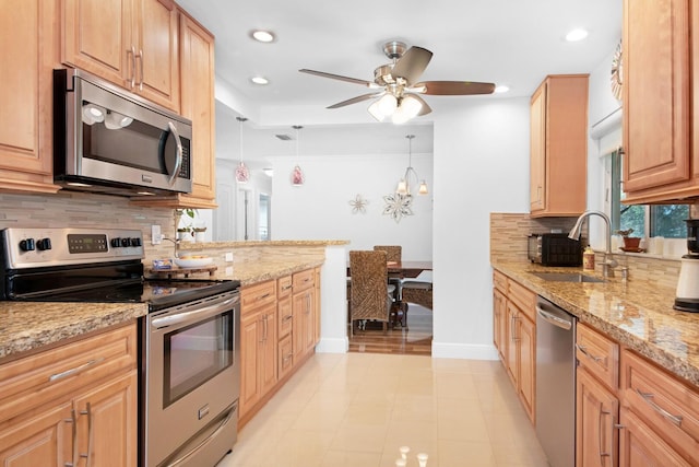 kitchen featuring decorative backsplash, light stone countertops, stainless steel appliances, and a sink