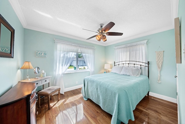 bedroom featuring ornamental molding, a textured ceiling, wood finished floors, baseboards, and ceiling fan