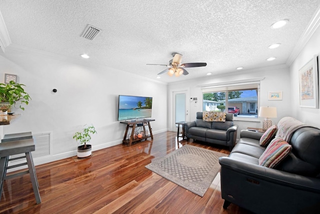 living room featuring visible vents, baseboards, wood finished floors, and ornamental molding