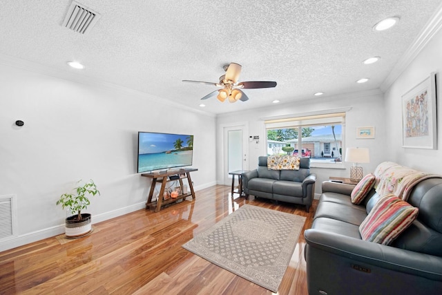 living room with visible vents, ornamental molding, baseboards, and wood finished floors