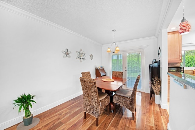 dining room with light wood-style flooring, a textured ceiling, and crown molding