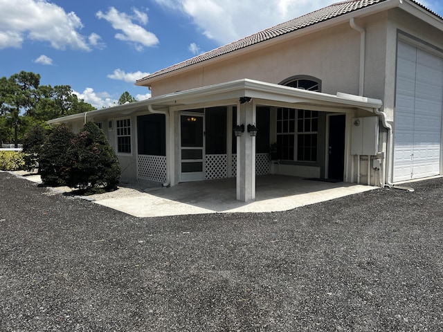 back of property with a garage, a tiled roof, and stucco siding