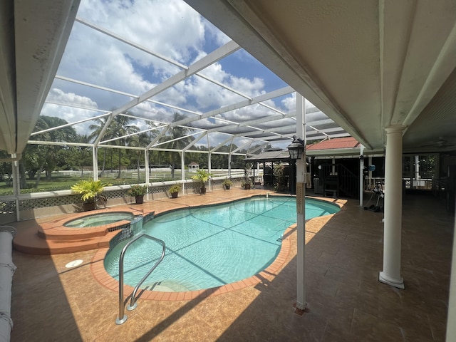 view of pool with a lanai, a pool with connected hot tub, and a patio