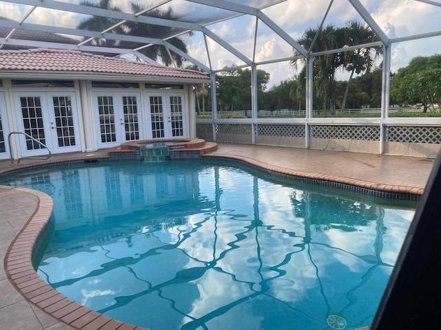 pool with glass enclosure, french doors, a patio area, and an in ground hot tub