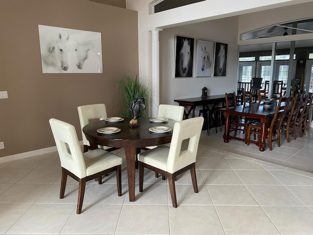 dining room featuring light tile patterned floors, decorative columns, and baseboards