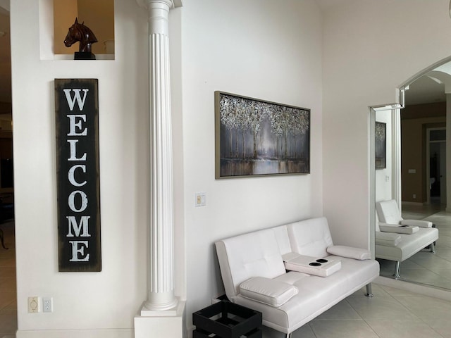 living area with decorative columns, arched walkways, and tile patterned floors