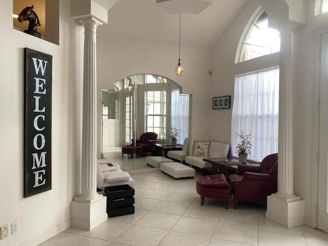 living room with high vaulted ceiling, ornate columns, and light tile patterned floors