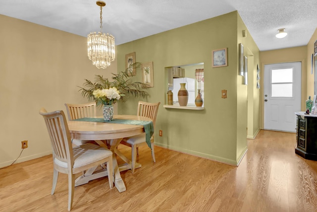 dining room featuring an inviting chandelier, light wood-style flooring, baseboards, and a textured ceiling