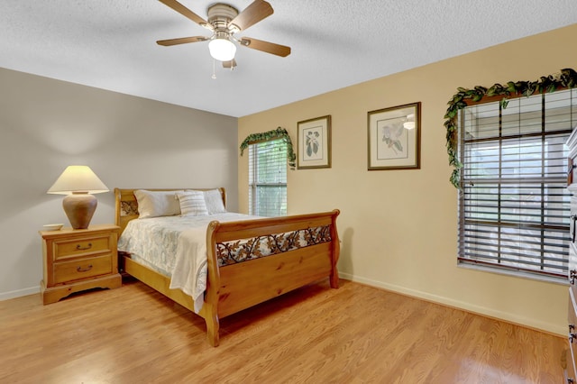 bedroom featuring a textured ceiling, baseboards, and light wood-style floors