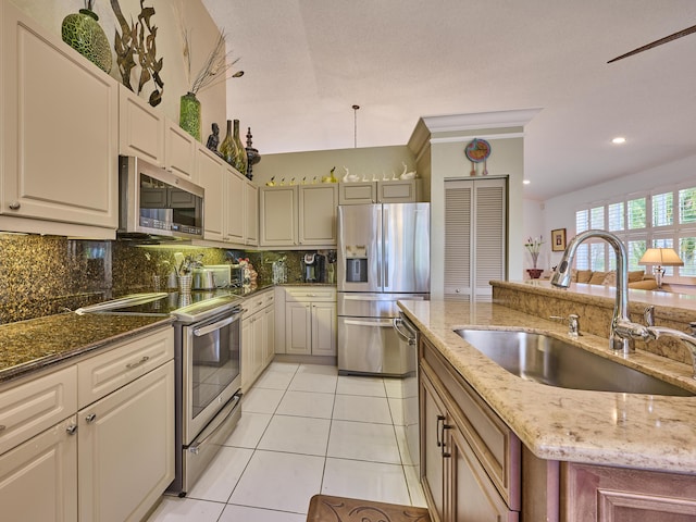 kitchen featuring light stone counters, light tile patterned floors, a sink, stainless steel appliances, and backsplash