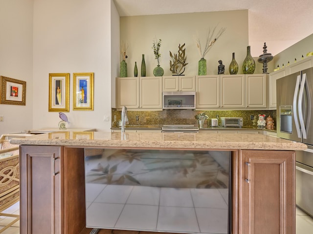 kitchen featuring light stone counters, stainless steel appliances, cream cabinetry, and decorative backsplash