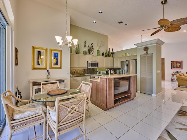 kitchen featuring high vaulted ceiling, stainless steel appliances, light countertops, cream cabinetry, and tasteful backsplash