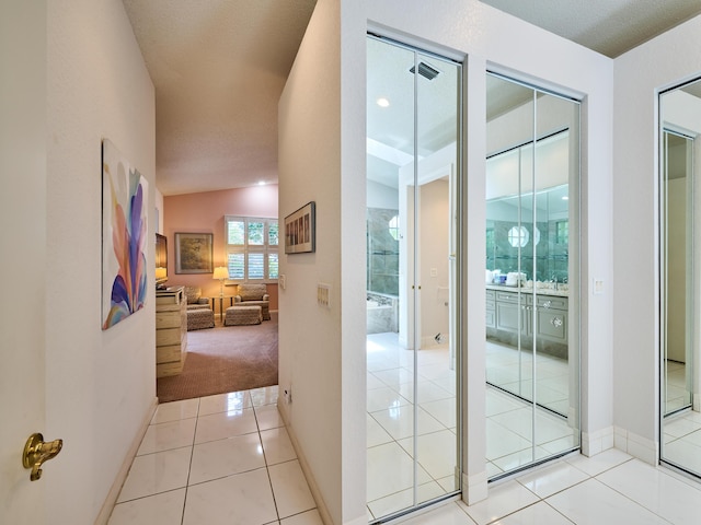 hall featuring light tile patterned floors, visible vents, light carpet, and baseboards