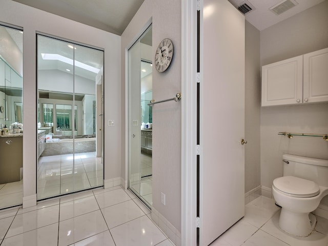 bathroom with vaulted ceiling with skylight, toilet, baseboards, and visible vents