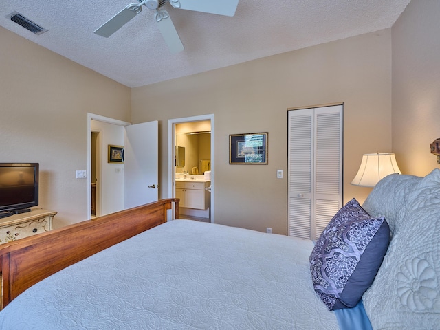 bedroom with a ceiling fan, visible vents, ensuite bath, a closet, and a textured ceiling