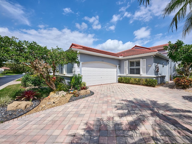 view of front of home with a tile roof, decorative driveway, a garage, and stucco siding