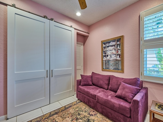 living room featuring recessed lighting, ceiling fan, a textured ceiling, a barn door, and a textured wall