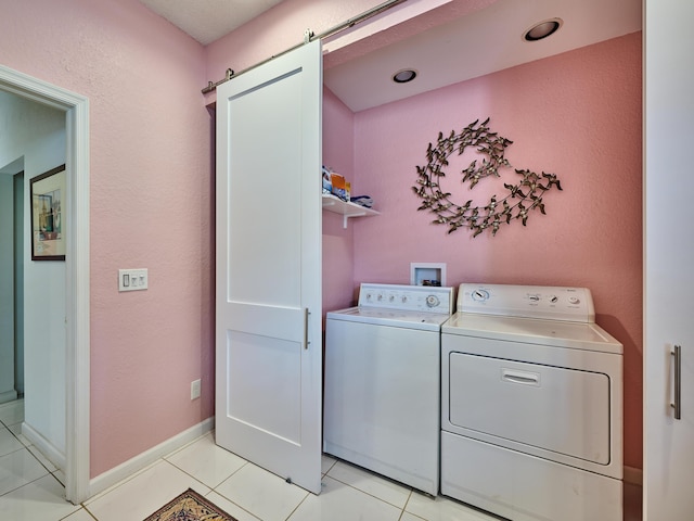 laundry area featuring light tile patterned floors, laundry area, washing machine and dryer, and a barn door