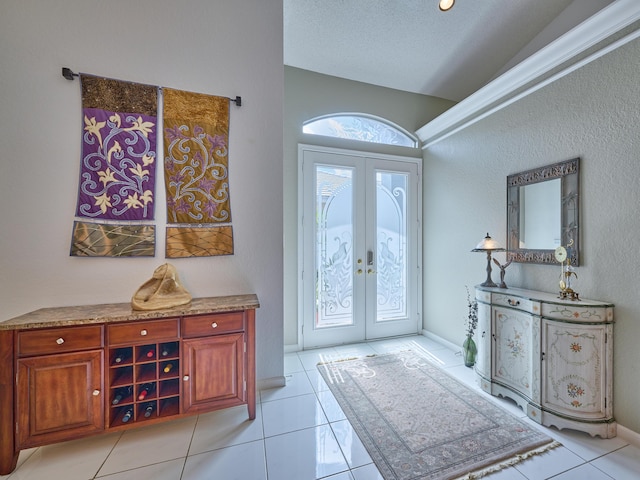 entrance foyer with baseboards, lofted ceiling, light tile patterned floors, french doors, and a textured ceiling