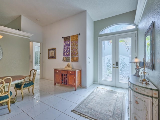 foyer entrance featuring lofted ceiling, light tile patterned floors, french doors, and baseboards