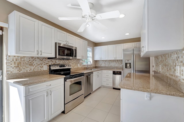 kitchen with a sink, a ceiling fan, white cabinets, appliances with stainless steel finishes, and tasteful backsplash