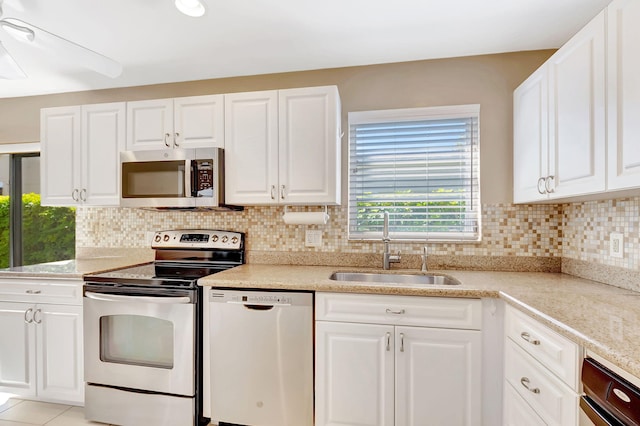 kitchen featuring appliances with stainless steel finishes, white cabinets, a sink, and decorative backsplash