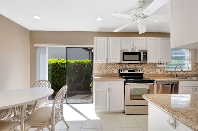 kitchen with appliances with stainless steel finishes, white cabinets, a sink, and backsplash