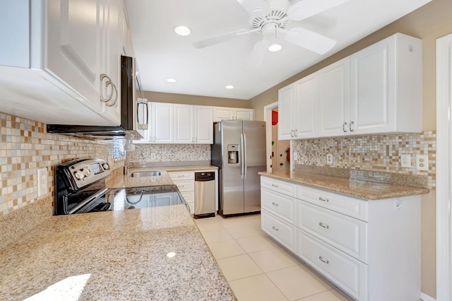 kitchen with white cabinets, decorative backsplash, light stone countertops, stainless steel appliances, and light tile patterned flooring